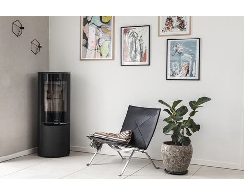 Vardagsrum med kamin, fåtölj, krukväxt och väggdekoration