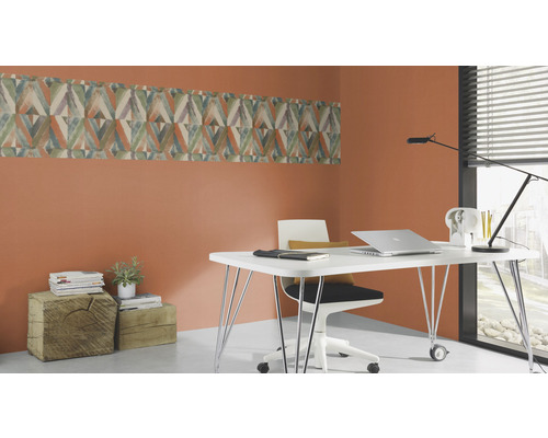 Kontor med skrivbord, stol och vägglist med geometriskt mönster