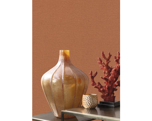 Dekorativ scen med vas, korall och ljusstake på ett bord framför en vägg