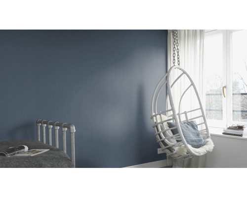 Ljus, modern sovrumsinredning med gungstol, säng och blåmålad vägg