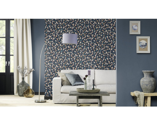 Vardagsrum med mönstrad tapet, soffa, golvlampa och dekoration