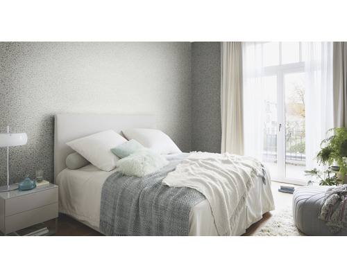 Sovrum med säng, nattduksbord och mönstrad tapet