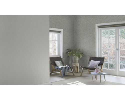 Ljust rum med mönstrad tapet, två trästolar och ett litet bord