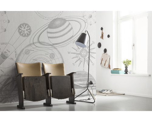 Rumsöversikt med tapet med planetmönster, teaterfåtölj och golvlampa