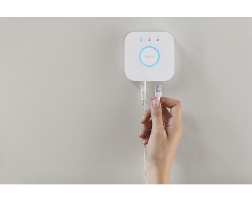 Philips Hue Bridge med nätverkskabel i handen