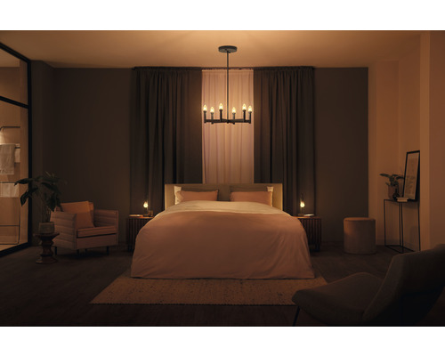 Sovrum med säng, sängbord, stol, fåtölj, taklampa och dekoration