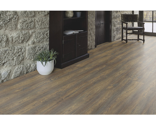 Interiör med brunt laminatgolv, stenvägg och mörka möbler