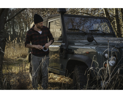 Man med tejp bredvid terrängfordon i fält