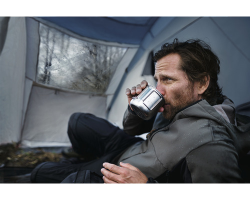 Man dricker ur en mugg i ett tält