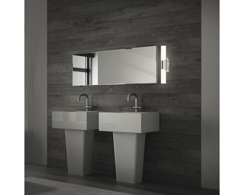 Badrum med två handfat, spegel och vägglampa framför trävägg