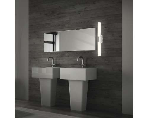 Badrum med två handfat, spegel och vägglampa.