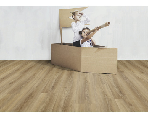 Två barn leker i en kartong på ett laminatgolv.