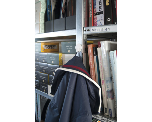 Jacka hänger på en krok i en bokhylla med böcker och mappar.