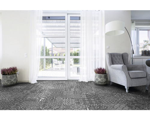 Vardagsrum med mönstrat vinylgolv, fåtölj och krukväxter framför en altandörr