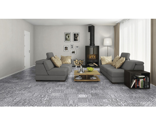 Vardagsrum med grått golv i lapptäcksdesign, soffor, öppen spis och trämöbler