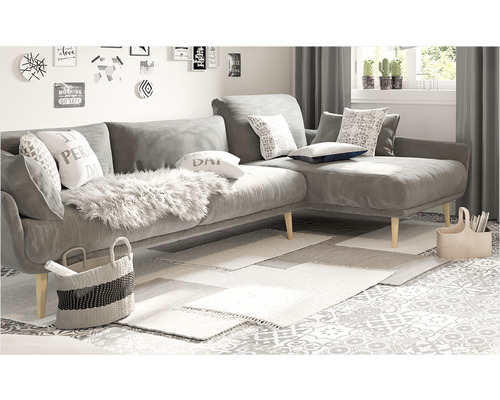 Vardagsrum med grå hörnsoffa, kuddar, mattor och dekorationer.