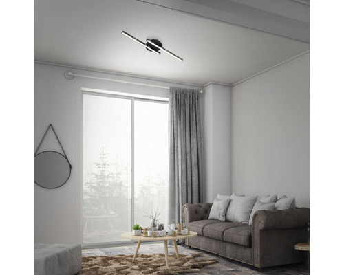 Vardagsrum med taklampa, soffa, gardin och fönster.