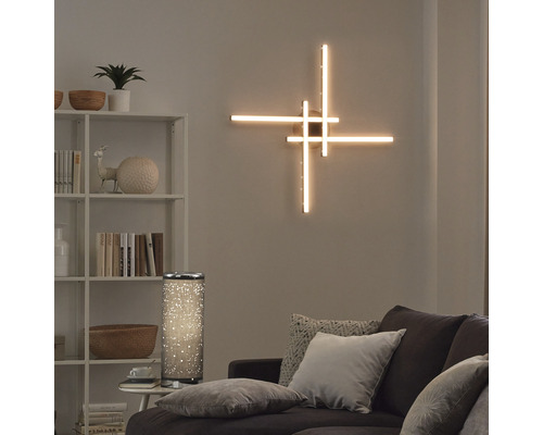 Vardagsrum med upplyst vägglampa, golvlampa, hylla och soffa.