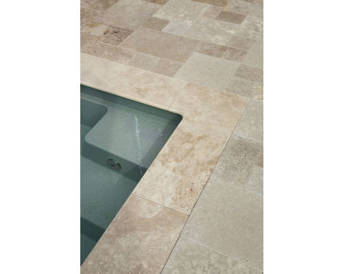 Detaljvy av en swimmingpool med travertinplattor