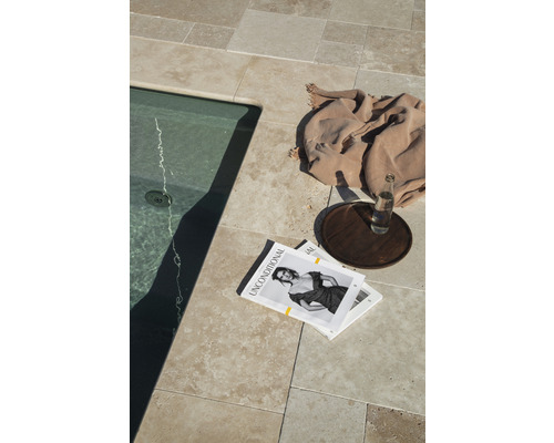 Scen med poolkant, golvplattor, filt, tidningar, dryck och bricka