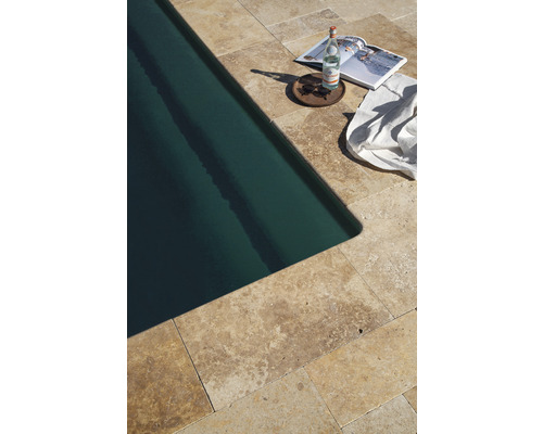 Pool med travertinplattor, vattenflaska, tidning, solglasögon och handduk
