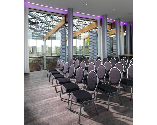 Interiör med stolsrader, trägolv och fönsterparti