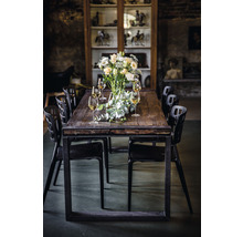 Matbord med blomsterarrangemang, glas och svarta stolar i ett rum med vitrinskåp