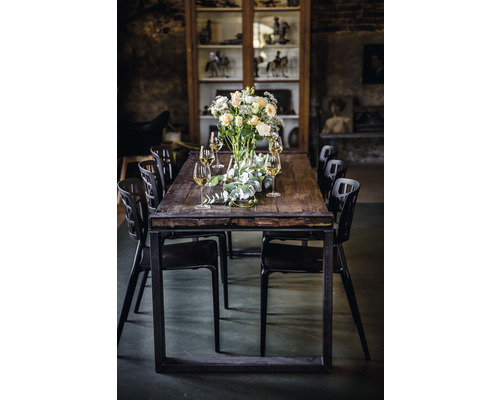 Matbord med blomsterarrangemang, glas och svarta stolar i ett rum med vitrinskåp