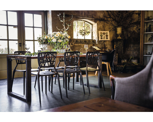 Matbord med stolar i ett ljust rum med rustik inredning och blommor