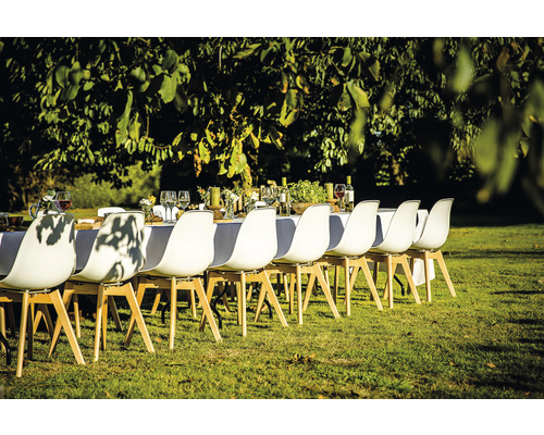 Scen av ett dukat bord utomhus med vita stolar på en gräsmatta