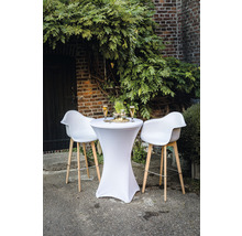 Ståbord med stretchöverdrag och barstolar framför en tegelvägg med växter