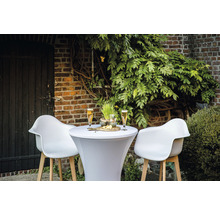 Utomhusscen med ståbord, två stolar, drycker och snacks framför en tegelvägg och växter.