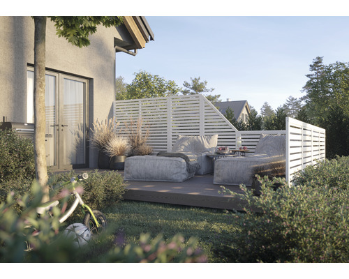 Uteplats med insynsskydd och loungemöbler i trädgården.