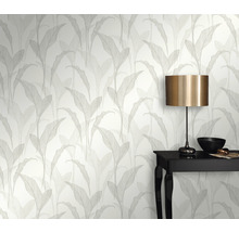 Rumsvy med tapet med bladmönster, bord och lampa