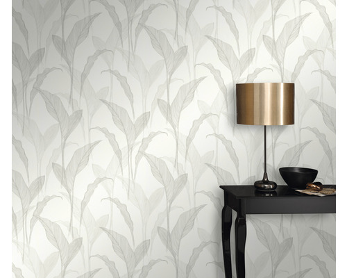 Rumsvy med tapet med bladmönster, bord och lampa