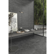 Modern interiör med mörka golv- och väggplattor, golvlampa och dekorativa element.