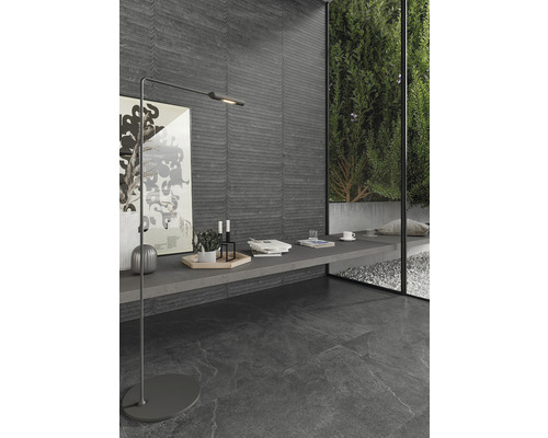 Modern interiör med mörka golv- och väggplattor, golvlampa och dekorativa element.