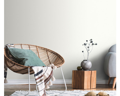 Dekorativt vardagsrum med rottingfåtölj, träbord och ljusa väggar