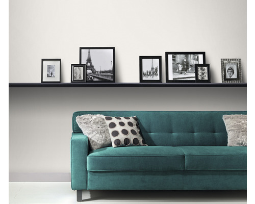 Modernt vardagsrum med turkos soffa, kuddar och en rad fotoramar på en hylla