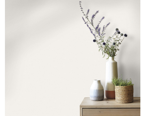 Dekorativa vaser med blommor på ett träbord framför en vägg