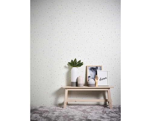 Dekorativ tapet med prickigt mönster i ett rum med ett litet bord med vaser och fotoramar på.