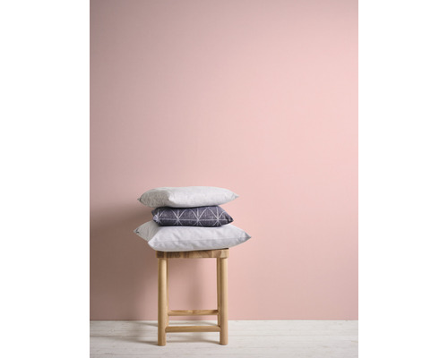 Dekorativa kuddar på en pall framför en vägg