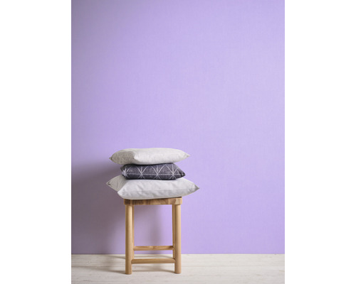 Dekorativa kuddar staplade på en pall framför en vägg