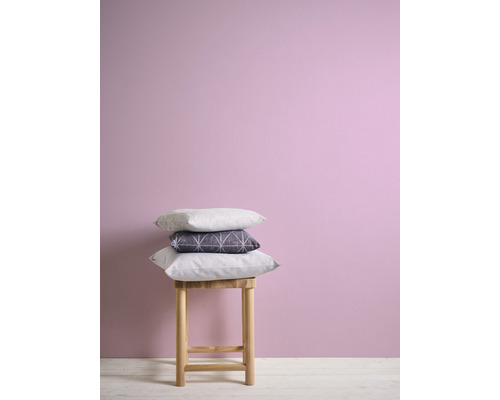 Dekorativa kuddar på en pall framför en vägg