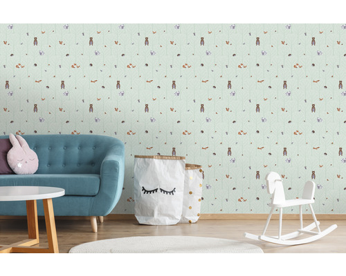 Barnrum med tapet med skogsdjursmotiv, en turkos soffa, ett runt bord och en gunghäst.