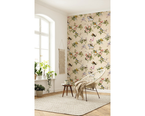 Ljust rum med blommig tapet, rund fåtölj och krukväxter