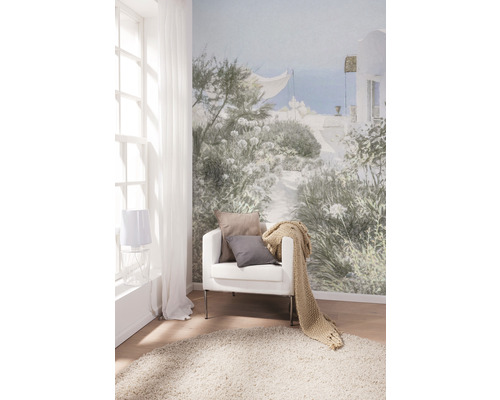 Vardagsrum med fotovägg, fåtölj, kuddar, överkast och matta för en ljus och vänlig atmosfär.