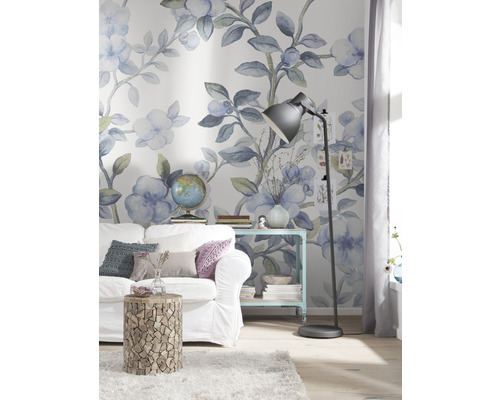 Dekorerat vardagsrum med soffa, sidobord och golvlampa framför en blommig tapet