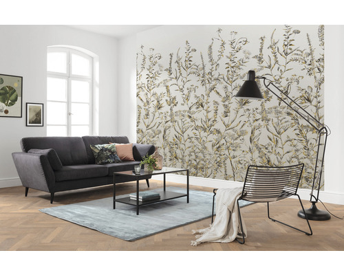 Vardagsrum med soffa, matta, golvlampa, stol och mönstrad tapet med växtmotiv