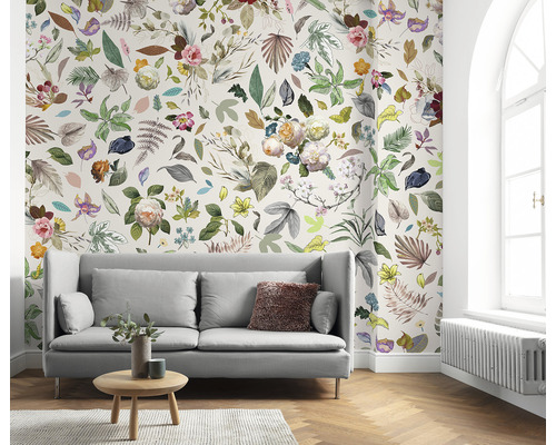 Vardagsrum med soffa och blommig tapet med blad och blommor.